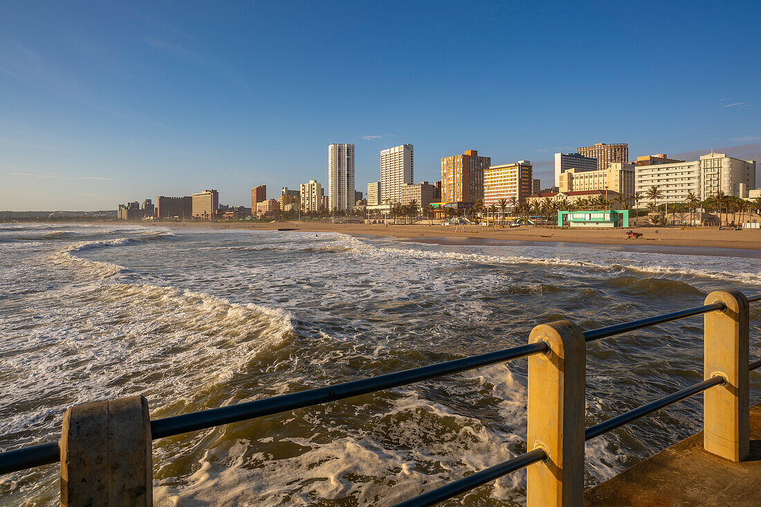 Blick auf Strandpromenade, Strand und Hotels vom Pier im Indischen Ozean bei Sonnenaufgang, Durban, Provinz KwaZulu-Natal, Südafrika, Afrika