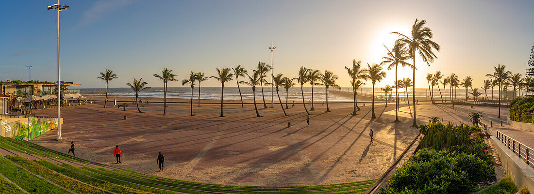 Blick auf Palmen, Promenade und den Indischen Ozean im Hintergrund bei Sonnenaufgang, Durban, Provinz KwaZulu-Natal, Südafrika, Afrika