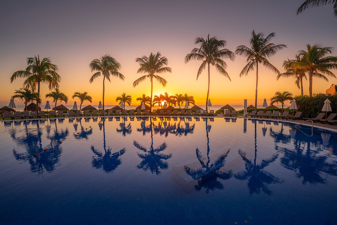 Blick auf Sonnenaufgang und Palmenreflexionen im Hotelpool bei Puerto Morelos, Karibikküste, Yucatan-Halbinsel, Mexiko, Nordamerika