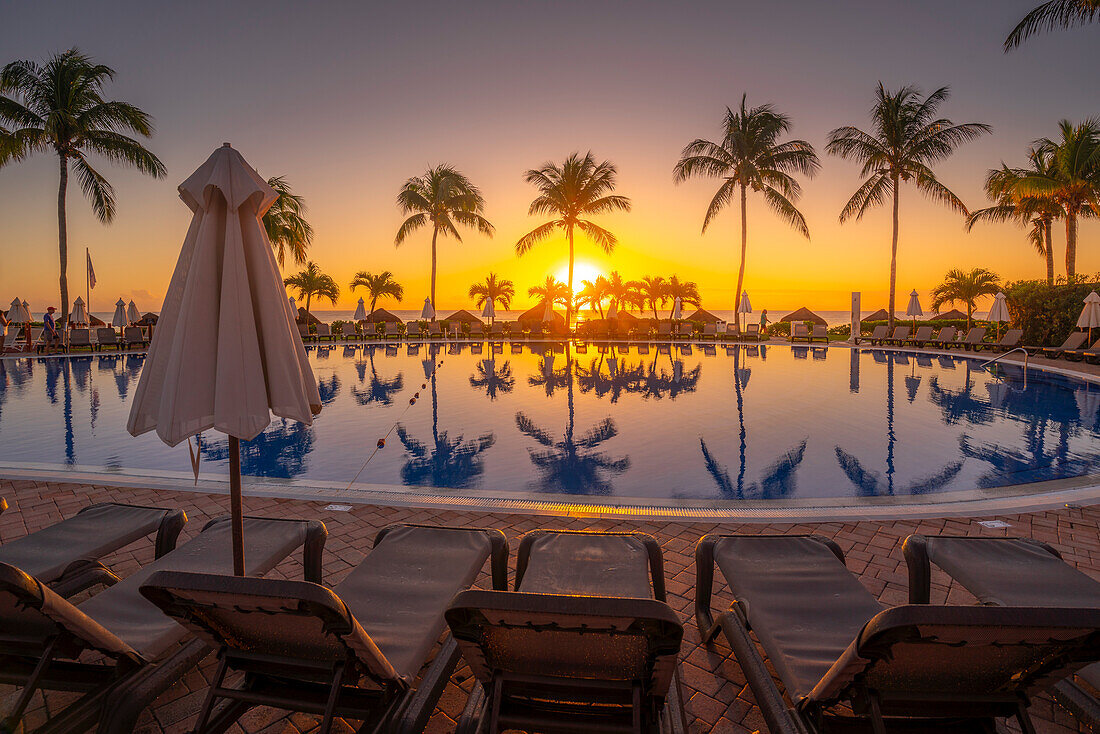 Blick auf Sonnenaufgang und Palmenreflexionen im Hotelpool bei Puerto Morelos, Karibikküste, Yucatan-Halbinsel, Mexiko, Nordamerika