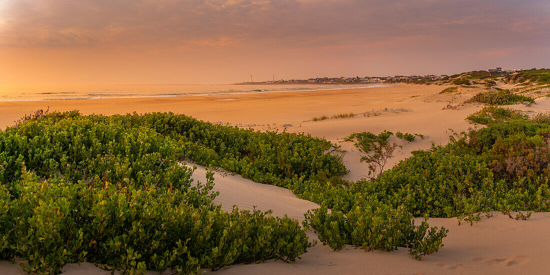 Blick auf Sanddünen und Strand mit Seal Point Lighthouse im Hintergrund bei Sonnenaufgang, Cape St. Francis, Ostkap-Provinz, Südafrika, Afrika