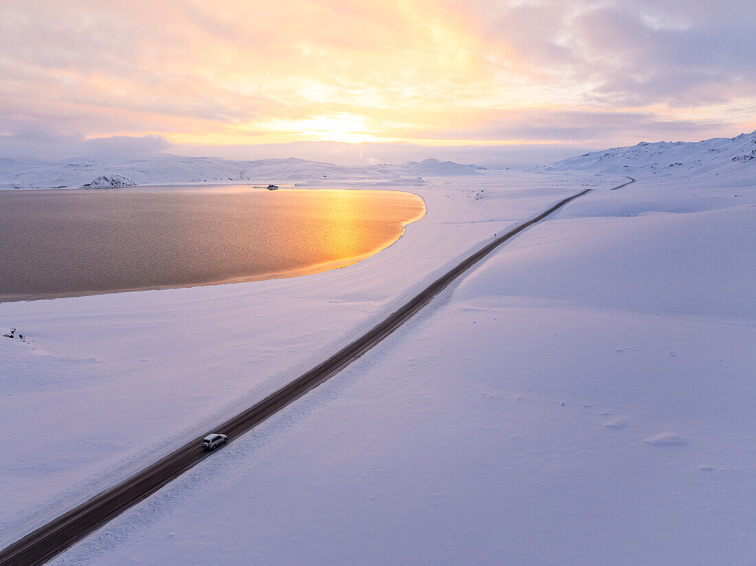 Aerial view by the drone of a car driving along the road that runs alongside Lake Kleifarvatn, during a magnificent winter sunset, Iceland, Polar Regions