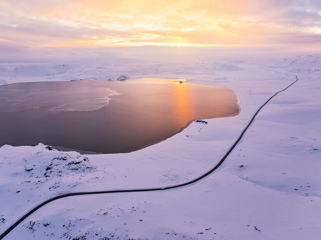 Aerial view taken by the drone of a car driving along the road that runs alongside Lake Kleifarvatn, during a magnificent winter sunset, Iceland, Polar Regions