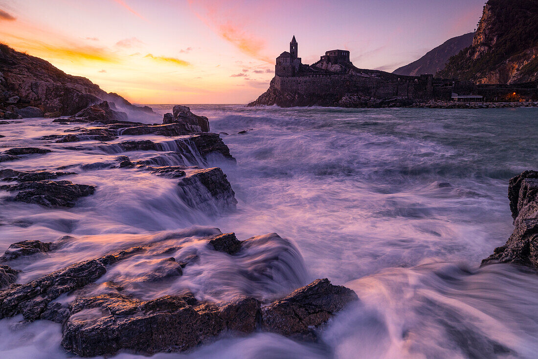 Warm light envelops the coast, during a beautiful sunset, San Pietro church, Portovenere (Porto Venere), UNESCO World Heritage Site, La Spezia, Liguria, Italy, Europe