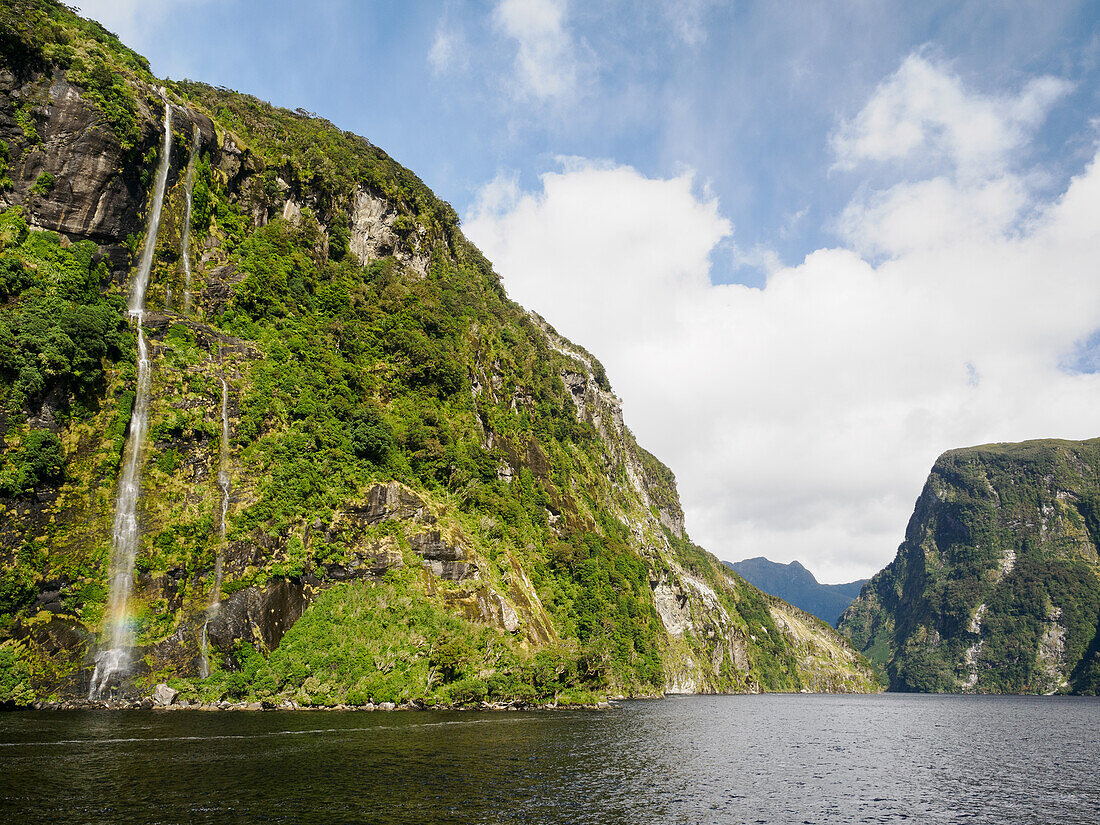 Wasserfall vor hoch aufragenden Klippen am Doubtful Sound, Fiordland National Park, Te Wahipounamu, UNESCO Weltnaturerbe, Südinsel, Neuseeland, Pazifik