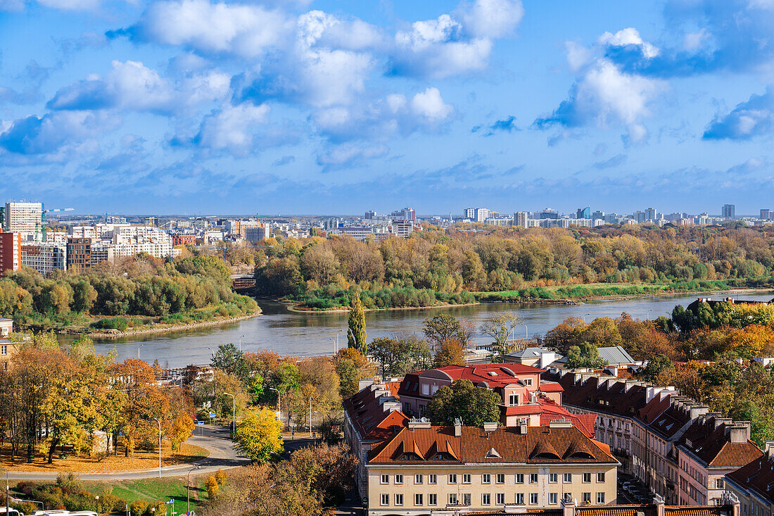 Landscape panoramic view of city skyline with houses and skyscrapers under a blue sky with clouds and greenery around Vistula River with Praga borough visible, Warsaw, Poland, Europe