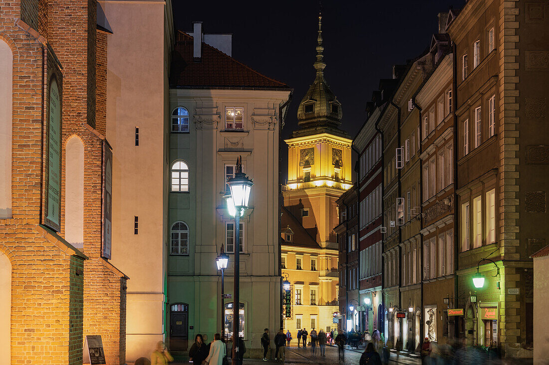 Niedrige Gebäude mit vorbeiziehenden Menschenmengen in der Nähe des Schlossplatzes (Plac Zamkowy), Swietojanska historische Allee bei Nacht, Altstadt, Warschau, Polen, Europa