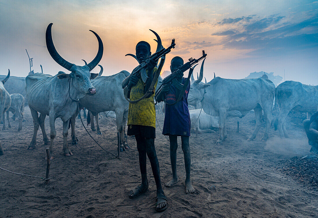 Junge Jungen mit Kalaschnikow posieren mit Kühen, Mundari-Stamm, Südsudan, Afrika