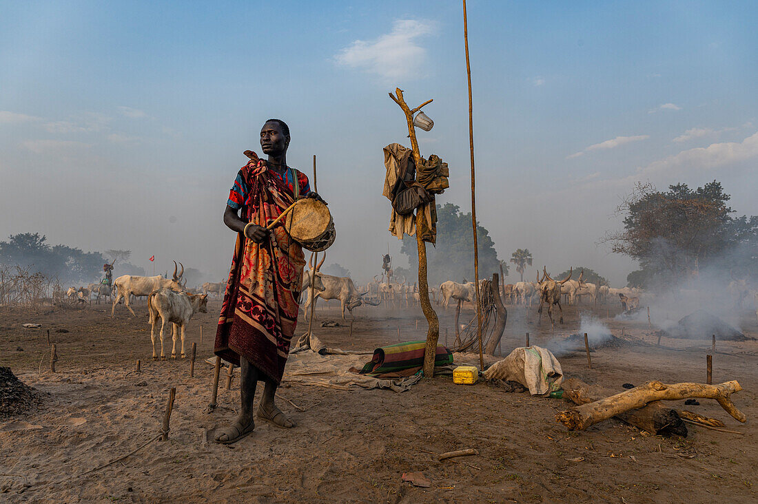 Mundari-Mann trommelt, um die Kühe zurückzurufen, Mundari-Stamm, Südsudan, Afrika