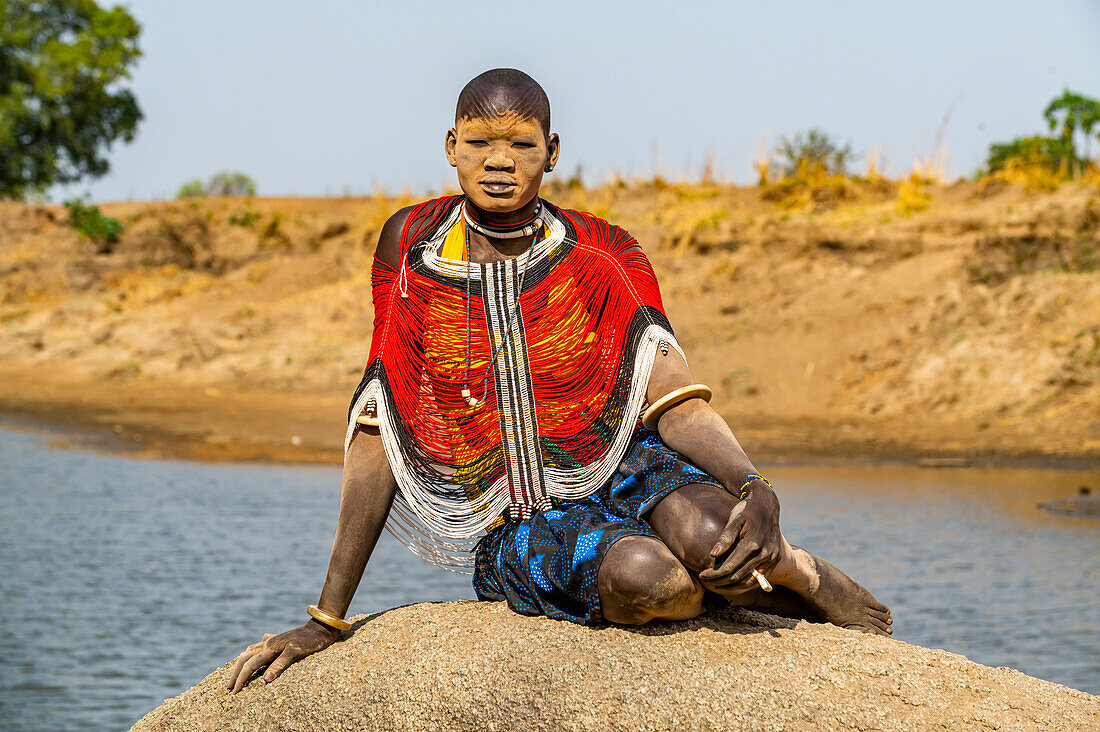 Mundari-Frau in traditioneller Kleidung mit Asche im Gesicht, posiert auf einem Felsen, Mundari-Stamm, Südsudan, Afrika