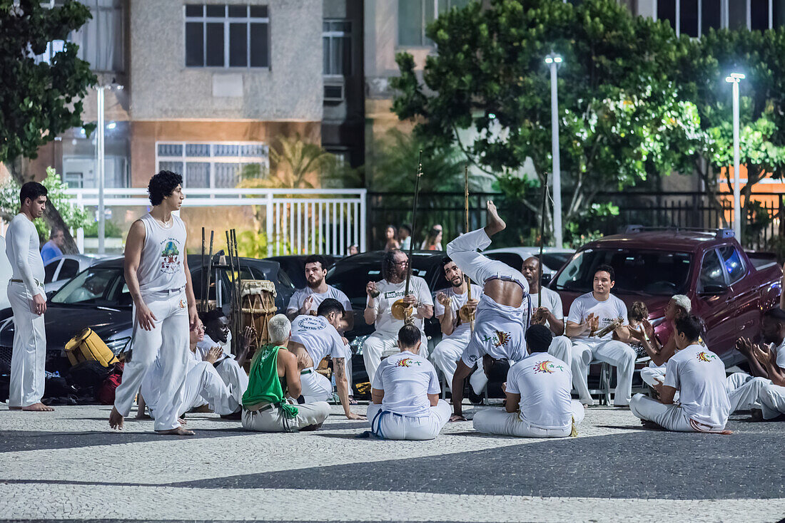 Menschen üben Capoeira, eine schnelle und vielseitige Kampfsportart, die in der Kolonialzeit auf den Kampf zwischen Sklaven und ihren Herren in Unterzahl oder bei technischem Nachteil ausgerichtet war, Copacabana, Rio de Janeiro, Brasilien, Südamerika