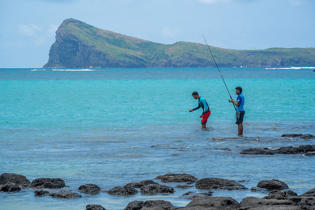 Blick auf Strand und Männer, die für ein lokales Restaurant fischen, an einem sonnigen Tag in Cap Malheureux, Mauritius, Indischer Ozean, Afrika