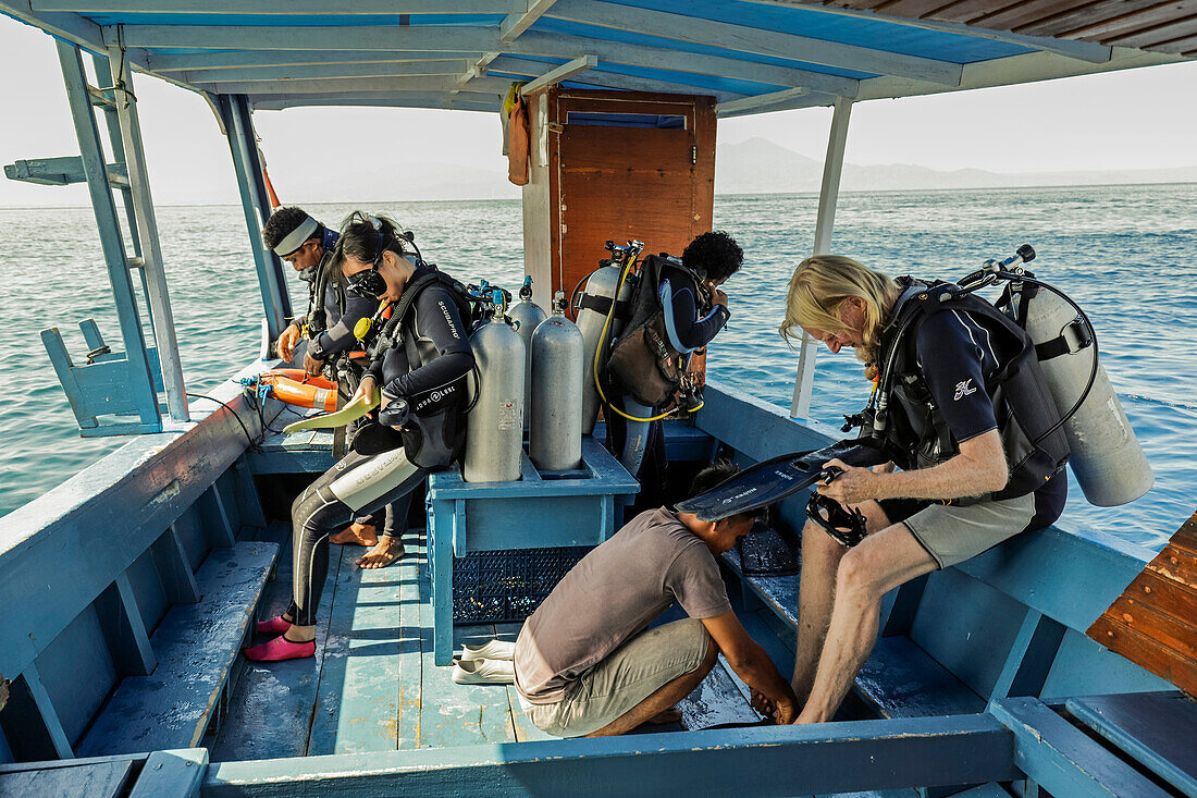 Taucher bereiten sich auf ein Boot vor dieser beliebten, von Korallen gesäumten Insel vor, die zum Tauchen und Schnorcheln einlädt, Bunaken, Nordsulawesi, Indonesien, Südostasien, Asien