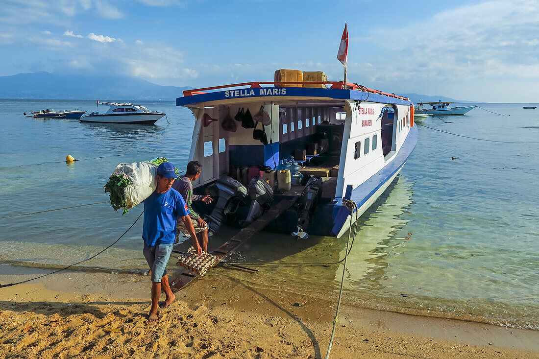 Männer entladen Ladung von der Fähre auf dieser von Korallen gesäumten Ferieninsel und Tauchdestination. Bunaken, Nordsulawesi, Indonesien, Südostasien, Asien