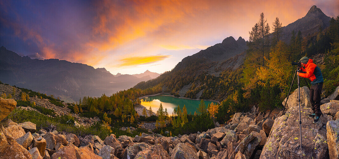 Panoramic view of a photographer at Lagazzuolo lake at sunrise during autumn, Chiesa di Valmalenco, Sondrio, Italy, Europe