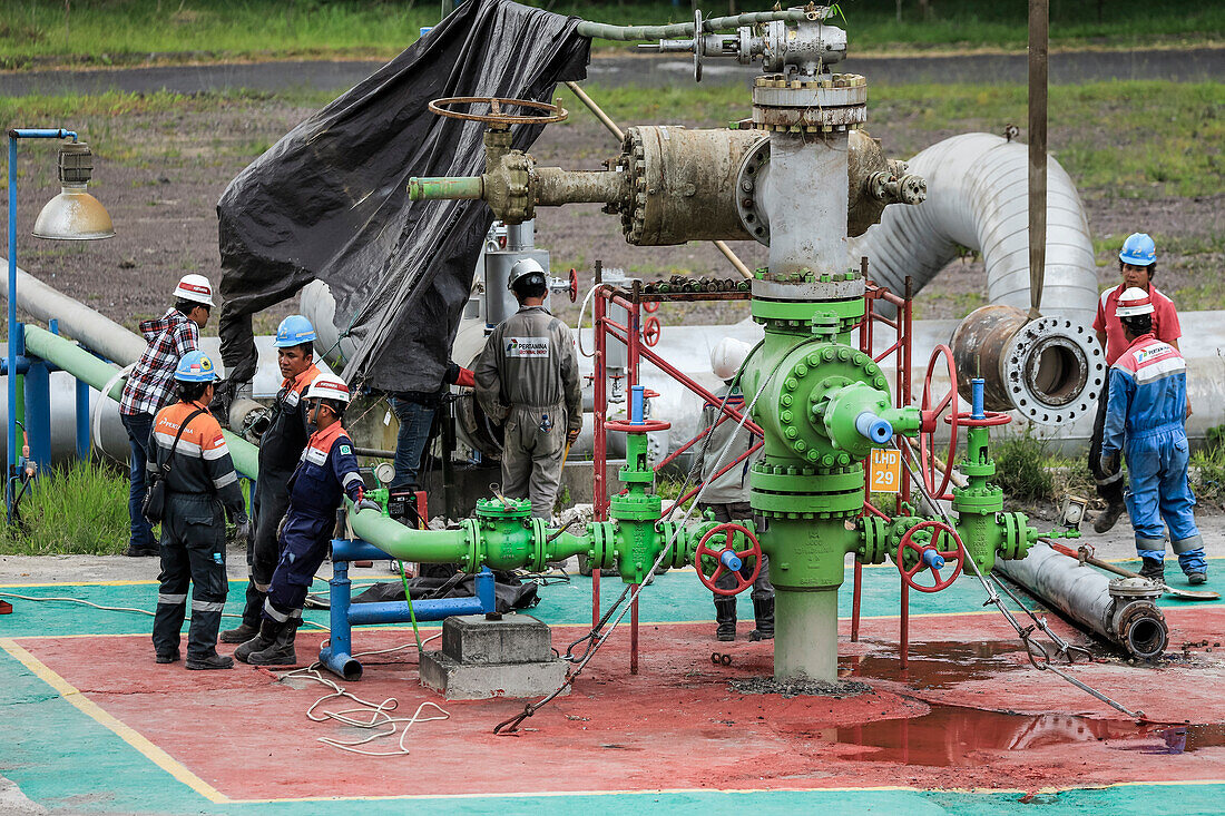 Arbeiter mit Schutzhelmen an Dampfrohren und Ventilen in einer von Pertamina Geothermal Energy betriebenen vulkanischen Anlage in der Nähe der Stadt Tomohon, Lake Linow, Tomohon, Nordsulawesi, Indonesien, Südostasien, Asien