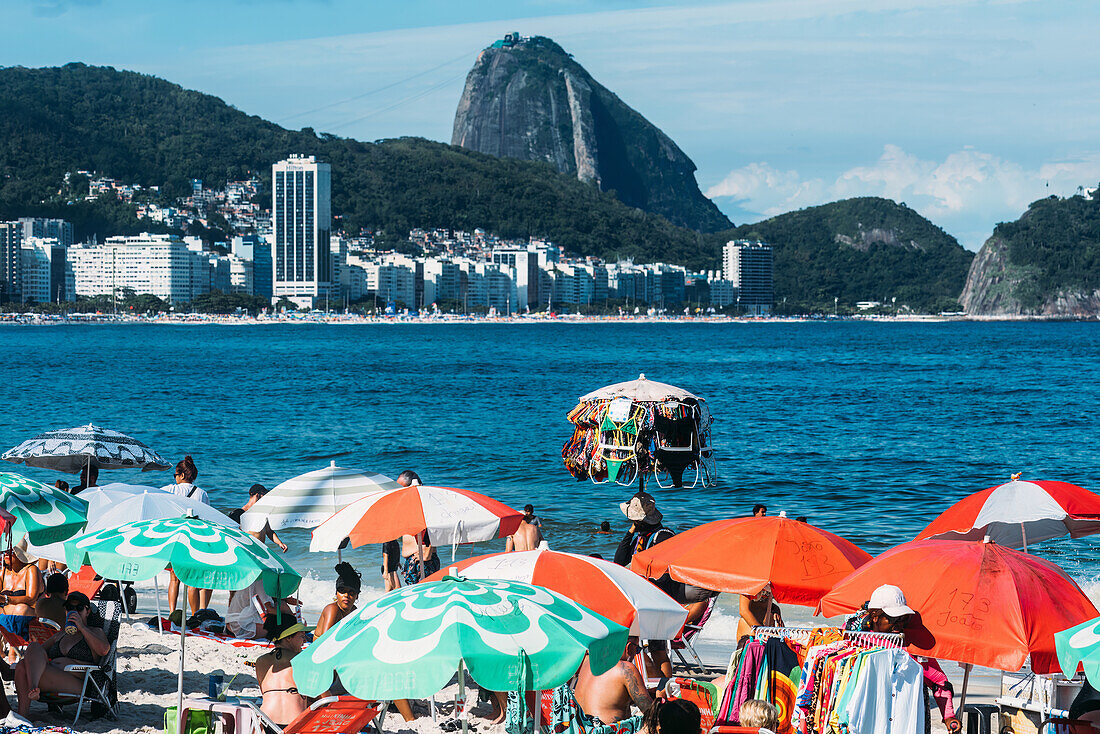 Mann verkauft Badeanzüge am Copacabana Beach mit dem berühmten Zuckerhut im Hintergrund, Rio de Janeiro, Brasilien, Südamerika