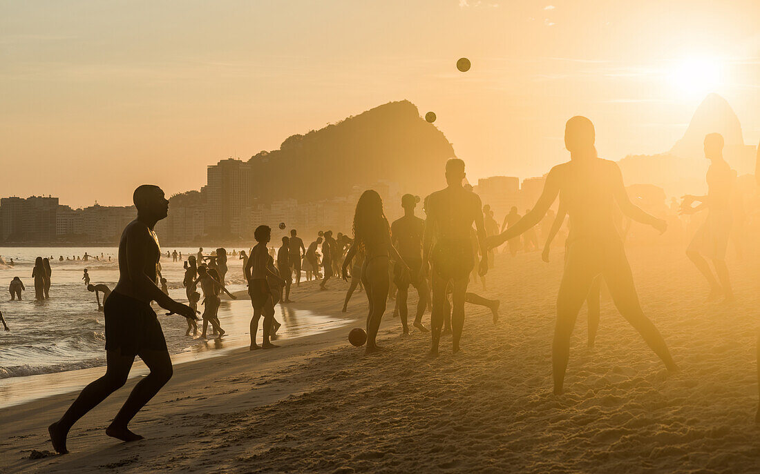 Menschen beim Sonnenuntergang, Copacabana Beach, Rio de Janeiro, Brasilien, Südamerika, die sich entspannen und "Keepy-uppy" spielen