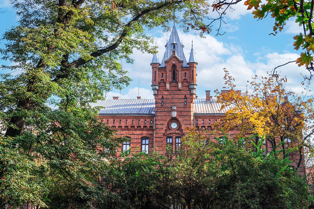 Low angle of traditional building of Municipal Headquarters of the State Fire Service surrounded by trees, Krakow, Poland, Europe