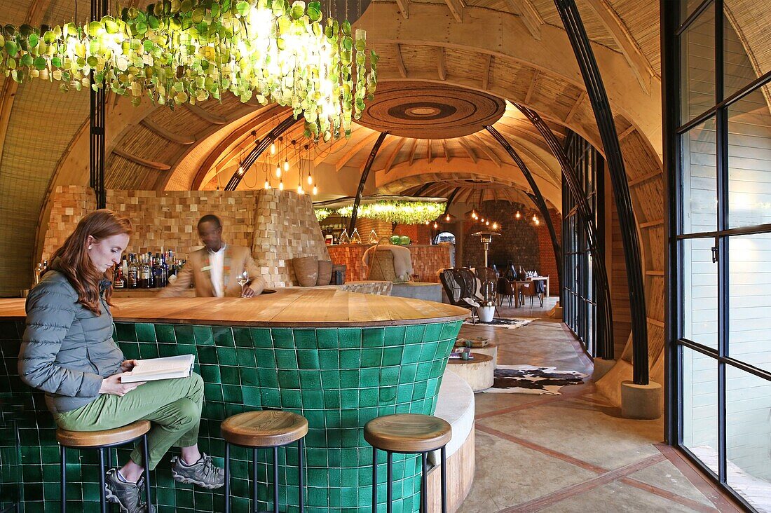 Rwanda, Volcanoes National Park, customer sitting at the bar of Bisate lodge, a lodge of Wilderness safaris group inspired by the former royal palace of Nyanza