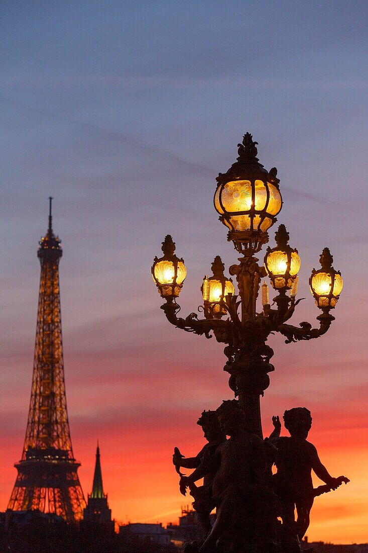 Frankreich, Paris, von der UNESCO zum Weltkulturerbe erklärtes Gebiet, die Putten, die eine Straßenlaterne von Henri Gauquie auf der Pont Alexandre III (Brücke Alexandre der Dritte) tragen, und der Eiffelturm im Hintergrund