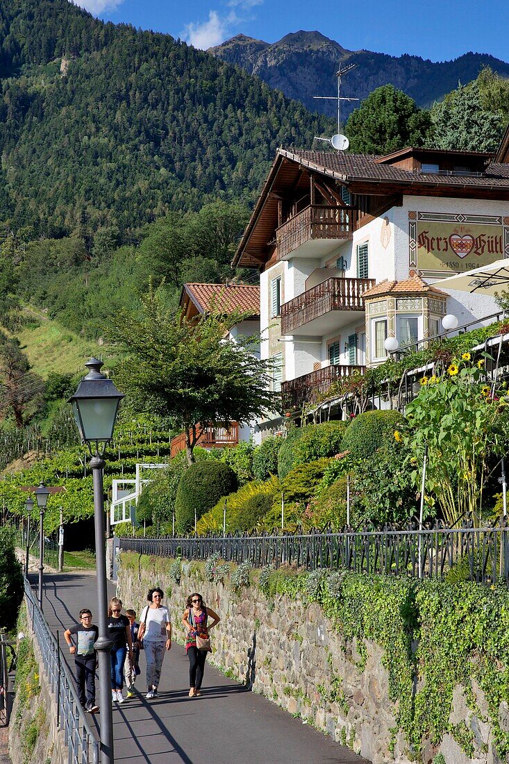 Italien, autonome Provinz Bozen, Tirol, Familie beim Spaziergang am Fuße einer Hütte in Tirol, dem Dorf, das der Region Tirol seinen Namen gab