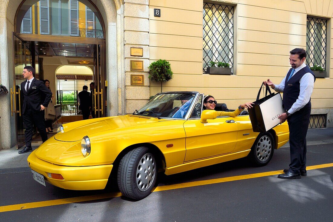 Italien, Lombardei, Mailand, Modeviereck (Quadrilatero della moda), gelbes Cabriolet Alfa Romeo Duetto Spider vor dem Four Seasons Hotel Milano, der Portier bringt eine Gucci-Tasche