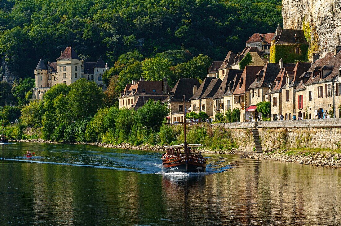 Frankreich, Dordogne, La Roque Gageac, Gabare ein traditionelles Boot, Häuser entlang der Dordogne und im Hintergrund das Schloss von Malartrie