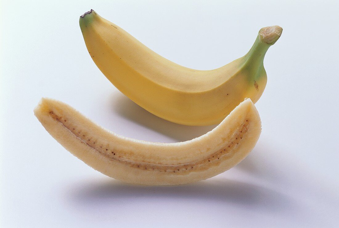 Ganze Banane und längs auf geschnittene Bananenhälfte