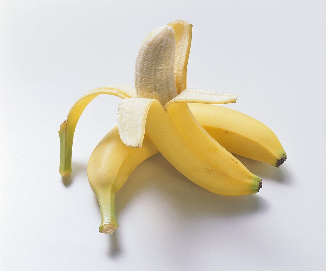 Half-peeled banana in front of whole banana