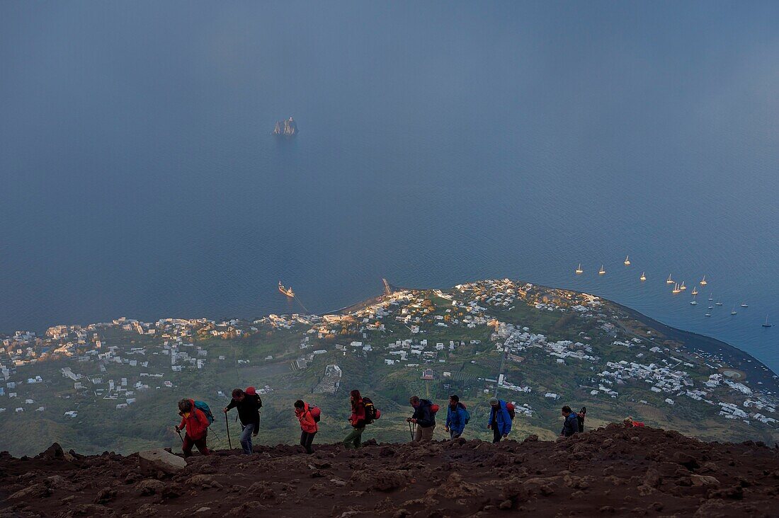 Italien, Sizilien, Äolische Inseln, von der UNESCO zum Weltnaturerbe erklärt, Insel Stromboli, Wanderer besteigen den Vulkan, im Hintergrund das Dorf Stromboli und die Insel Strombolicchio