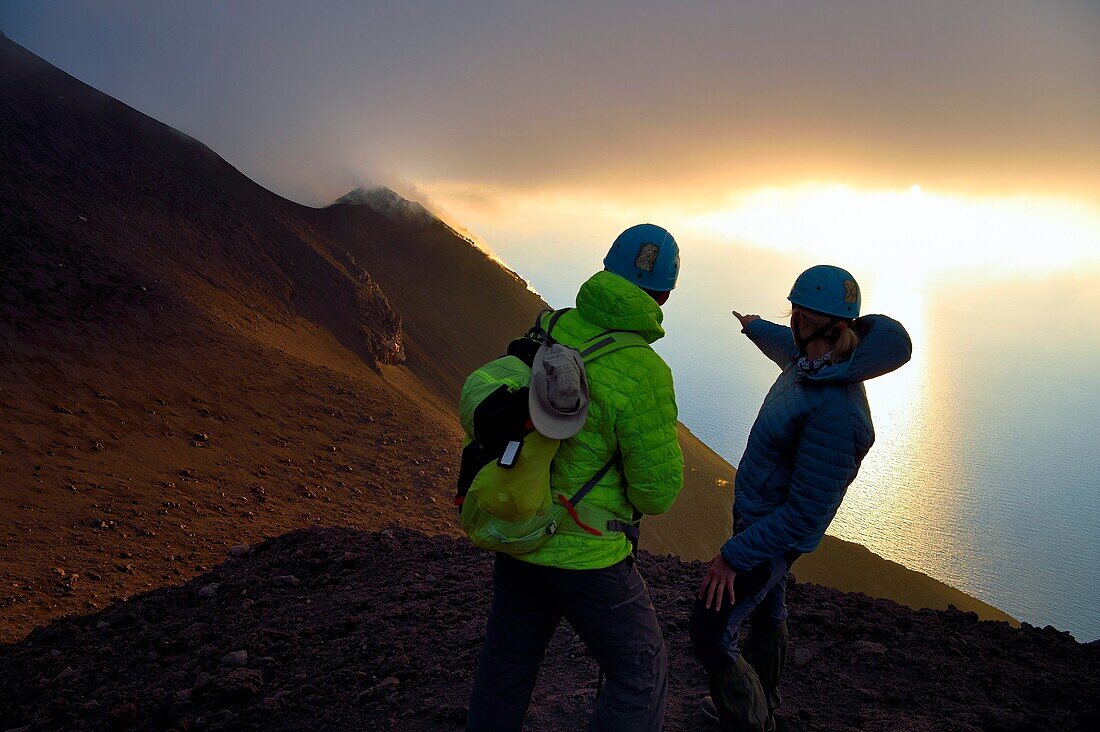 Italien, Sizilien, Äolische Inseln, von der UNESCO zum Weltnaturerbe erklärt, Insel Stromboli, Wanderer beobachten die Fumarolen an den Hängen des aktiven Vulkans bei Sonnenuntergang