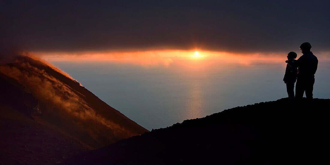 Italien, Sizilien, Äolische Inseln, von der UNESCO zum Weltnaturerbe erklärt, Insel Stromboli, Wanderer beobachten die Fumarolen an den Hängen des aktiven Vulkans bei Sonnenuntergang