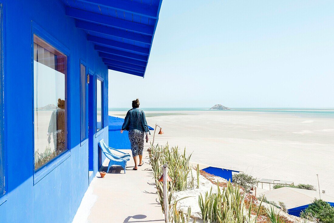 Marocco, Oued Ed-Dahab, Dakhla, Dakhla Attitude Resort, young woman on the terrace of a hotel room overlooking a bay at low tide