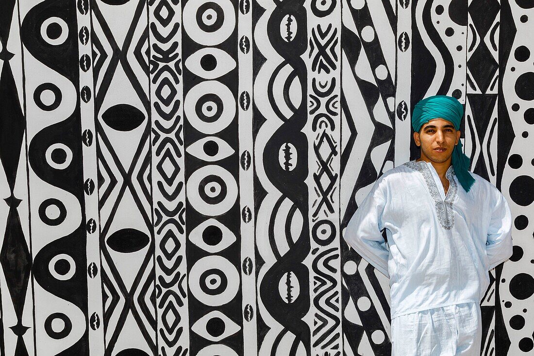 Marocco, Oued Ed-Dahab, Dakhla, Les Dunes Eco-lodge, young Moroccan in traditional clothes in front of a tent decorated with African tribal patterns