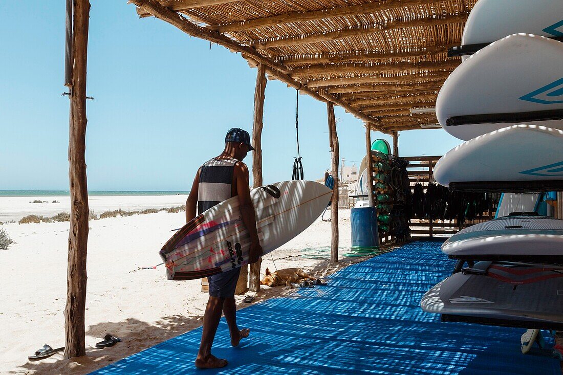 Marokko, Oued Ed-Dahab, Dakhla, Ocean Vagabond Lassarga Eco-lodge, Surfer in einer Hütte zur Lagerung von Brettern gegen das Licht, in einem Wüstenrahmen