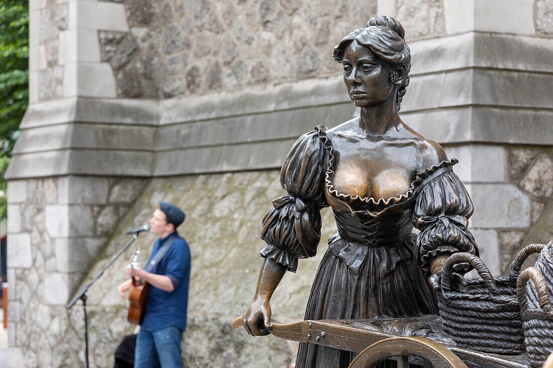 Ireland, Dublin, crossing of Saint Andrew's and Suffolk Street, the statue of Molly Malone, official anthem song of the city that tells the story of a beautiful fishmonger exercising her craft in the streets, commemorative statue designed by Jeanne Rynhart, tourists come to touch her breasts, in the background a street singer