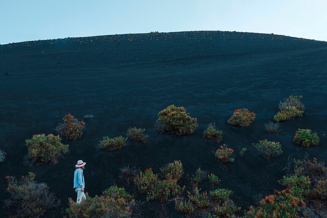 Spain, Canary Islands, La Palma, hiker on a trail in a desert and volcanic environment at sunrise