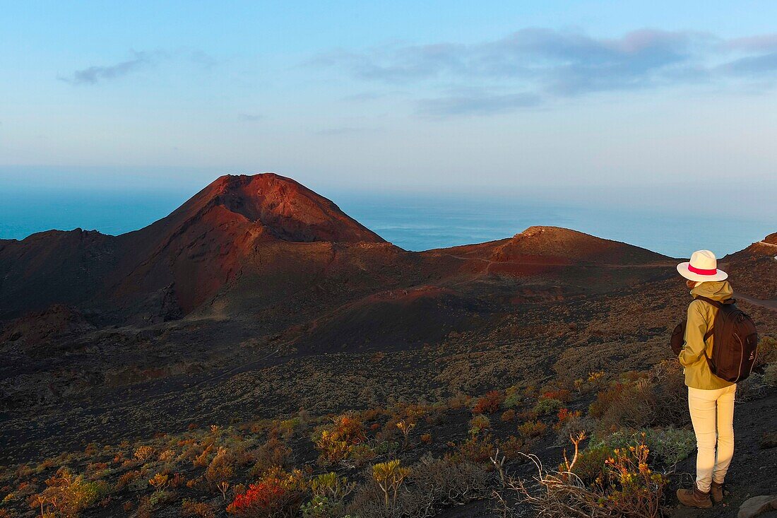 Spanien, Kanarische Inseln, La Palma, Wanderer auf einem Wanderweg in einer wüstenhaften und vulkanischen Umgebung bei Sonnenaufgang