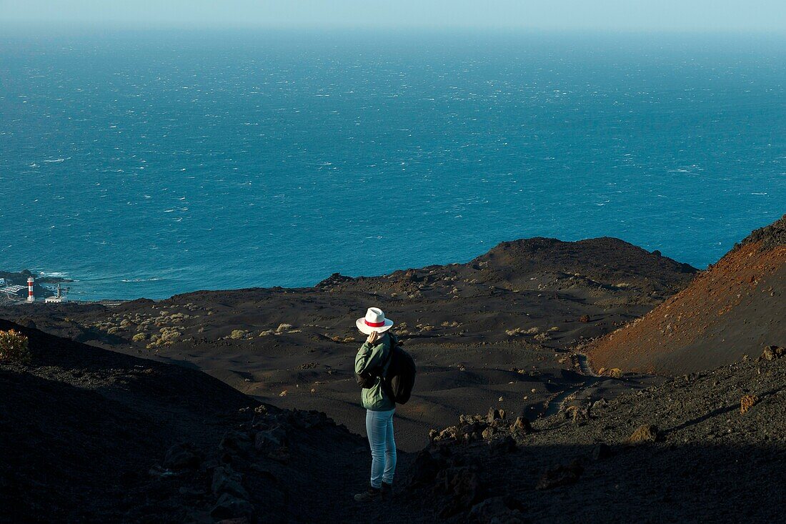 Spain, Canary Islands, La Palma, hiker on a trail in a desert and volcanic environment at sunrise