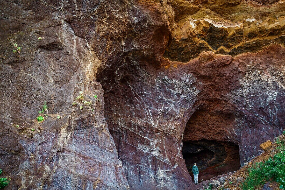 Spanien, Kanarische Inseln, La Palma, Touristen auf einem Wanderweg unter einem Gewölbe aus Vulkangestein am Meer