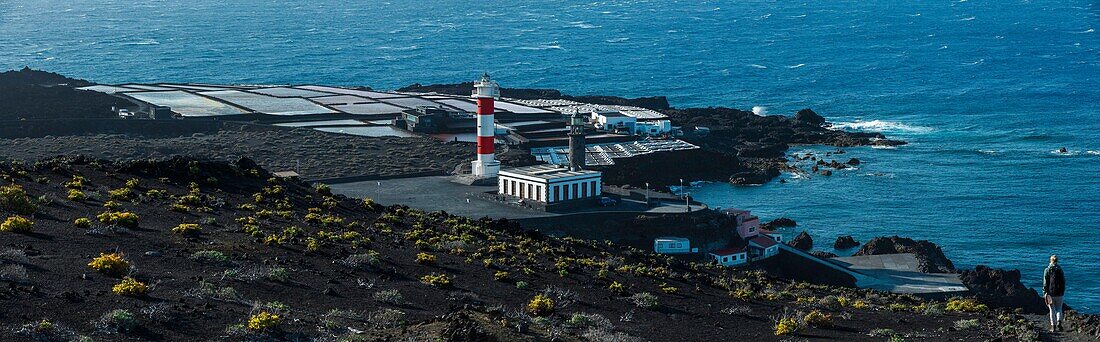 Spain, Canary Islands, La Palma, panoramic view of a lighthouse and saline that surround it by the sea, on a volcanic island