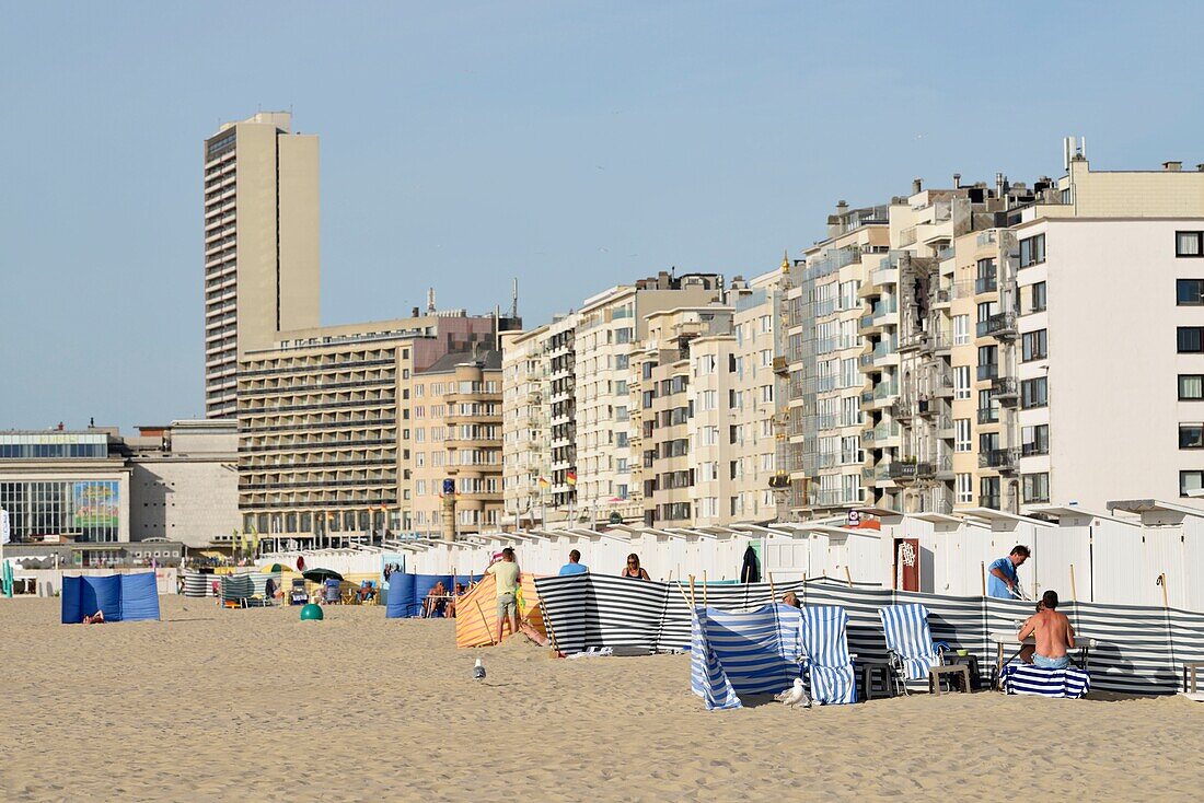 Belgium, West Flanders, Ostend, holidaymakers on the beach in front of the white cabins set along the seafront promenade