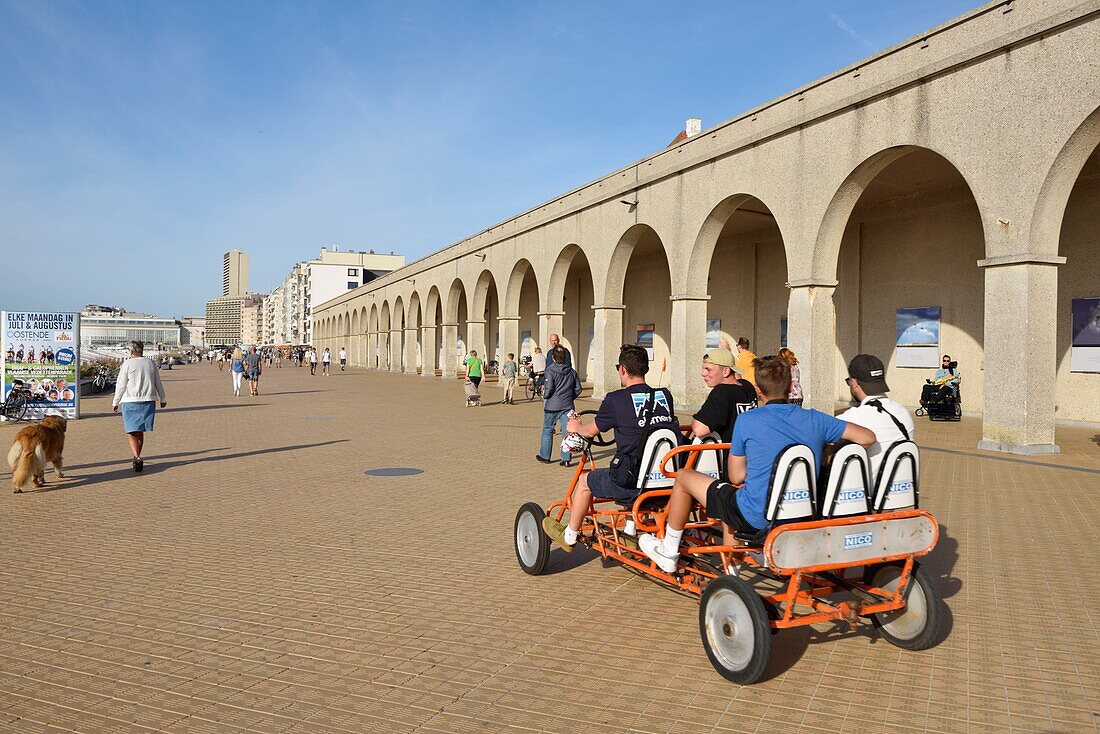 Belgium, West Flanders, Ostend, waterfront promenade, four young people driving a kart