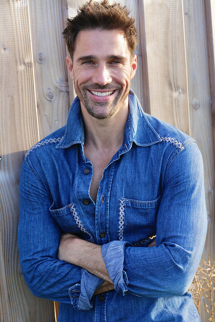 Laughing man in denim shirt, arms crossed