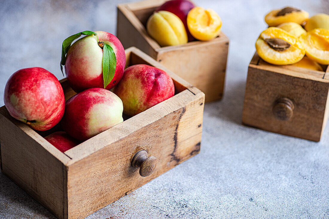 Ripe nectarines and peaches, displayed in rustic wooden crates, capture the essence of summer with their vibrant colors and juicy appearance. The wooden texture adds a natural, earthy feel to the image