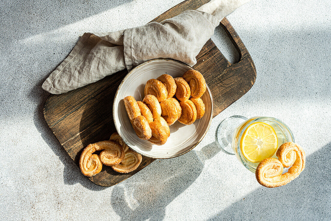 Palmiers oder Elefantenohren, Blätterteigkekse in einer Schale auf einem Betontisch an einem sonnigen Tag