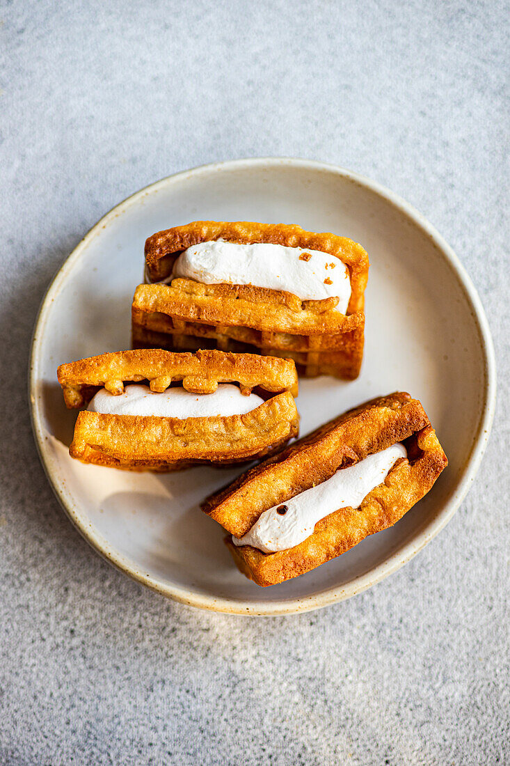 Golden homemade waffles with a fluffy vanilla marshmallow layer served in a ceramic plate