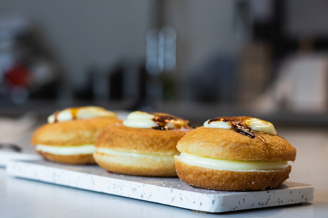 Süße vegane Berliner mit Zuckerkruste auf einem Brett und Sahne auf einem Tablett in einer Bäckerei