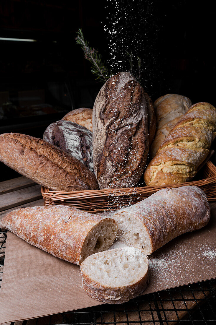 Eine Auswahl an frischem, handgemachtem Sauerteigbrot mit einladender Textur, mit Mehl bestäubt und in einem rustikalen Korb präsentiert.